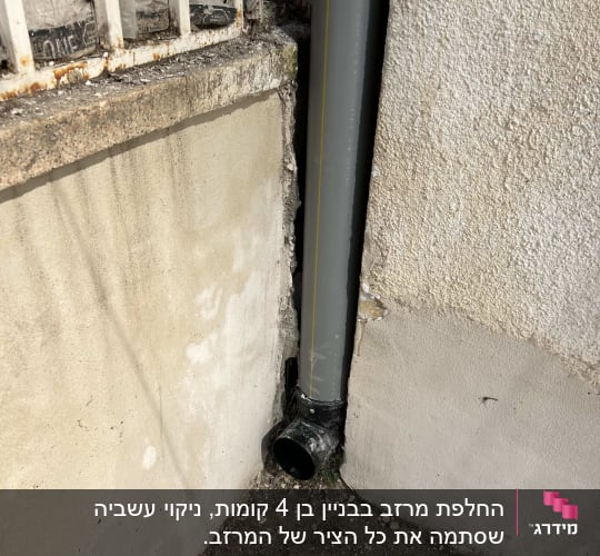 צינור ניקוז אפור מחובר לקיר חיצוני